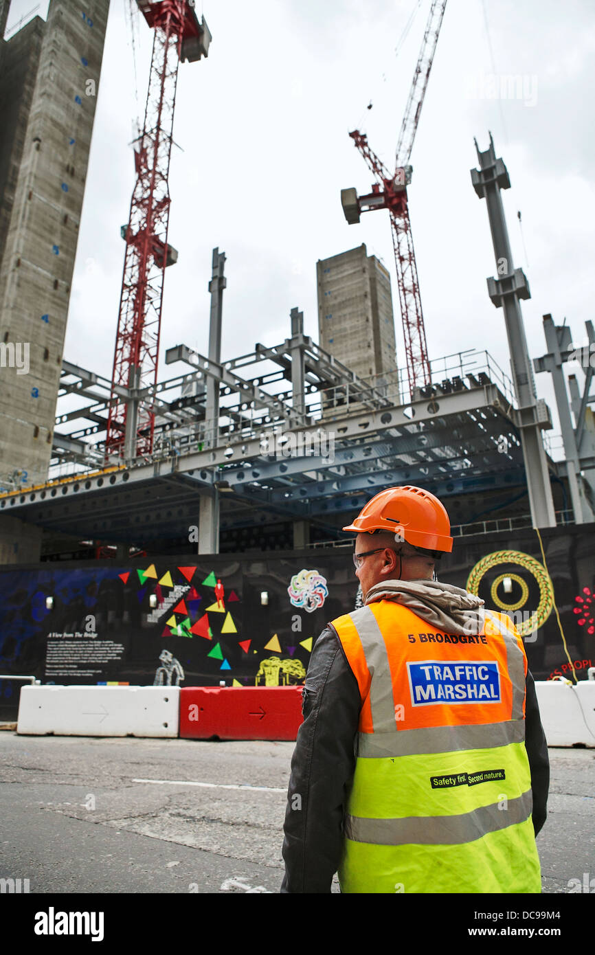 Traffic marshal stands opposite the construction building site of 5 Broadgate head -office of Switzerland's biggest bank - UBS. Stock Photo