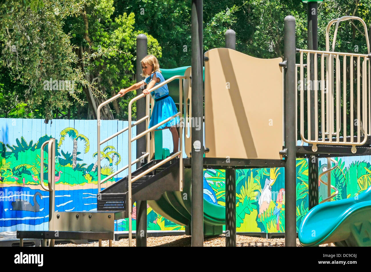 Young girl playing alone amongst the swings and slides at a playground