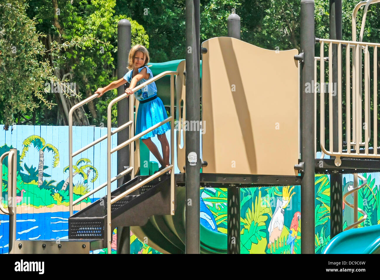 Young girl playing alone amongst the swings and slides at a playground