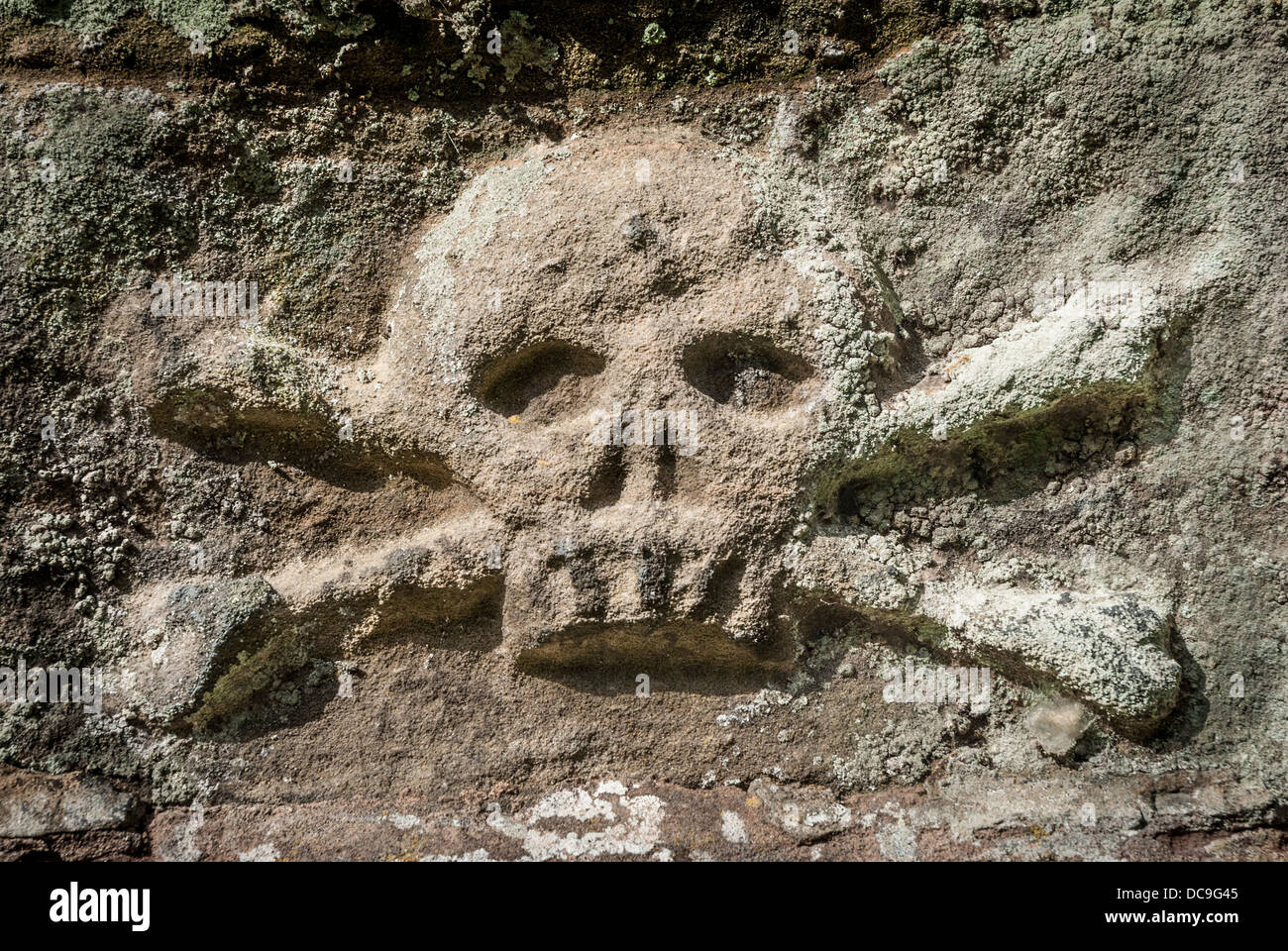 Ancient weathered stone skull and crossbones Stock Photo