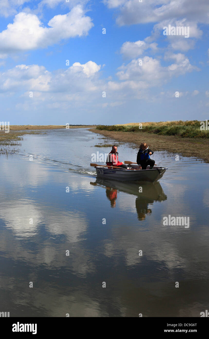 Father and son boating in a flooded creek at high tide on the North Norfolk coast. Stock Photo