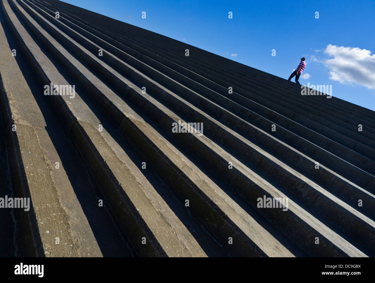 Man walking along the top of a sea wall. Stock Photo