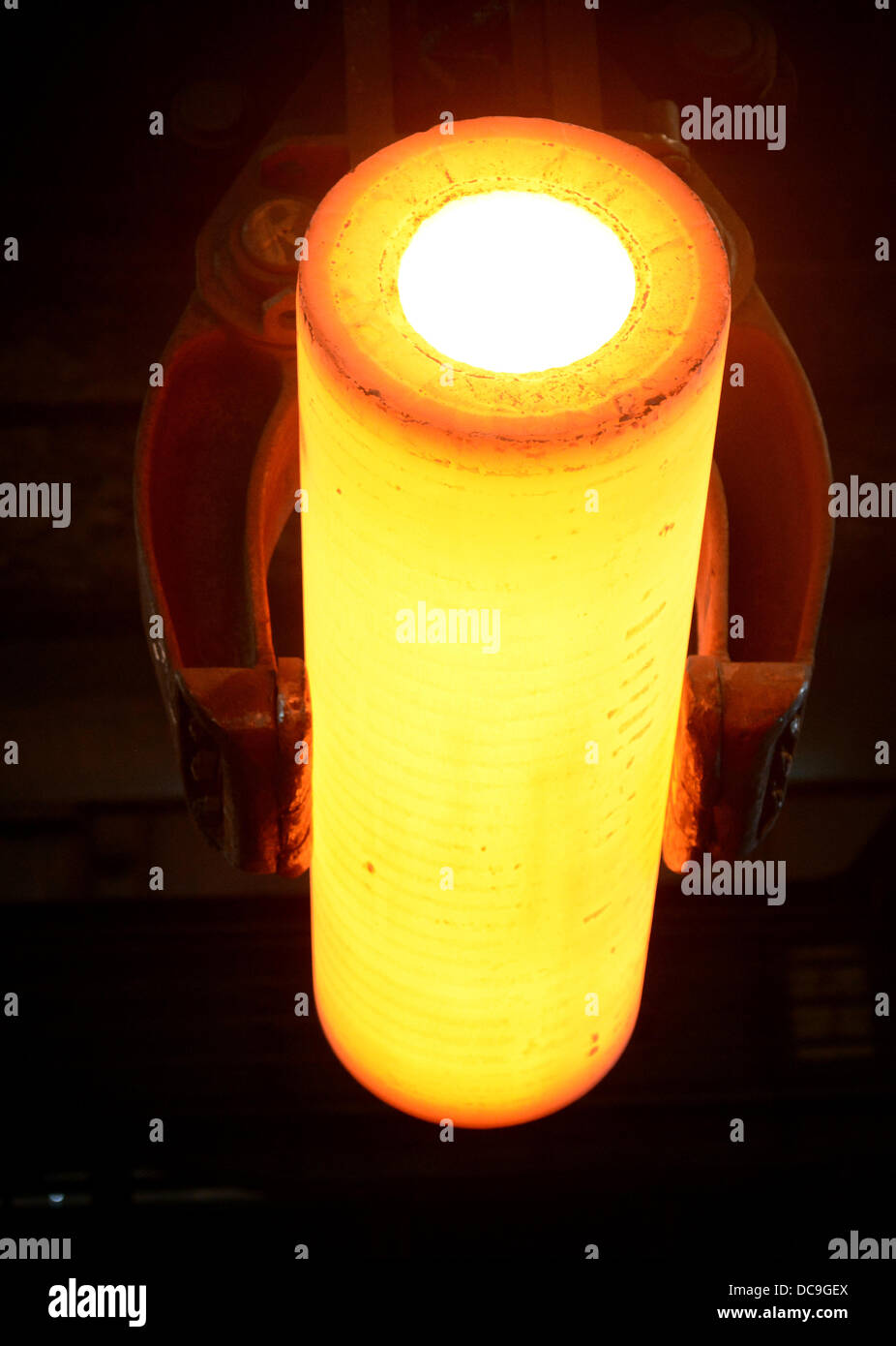 A glowing steel pipe is transported in the manufacturing hall at