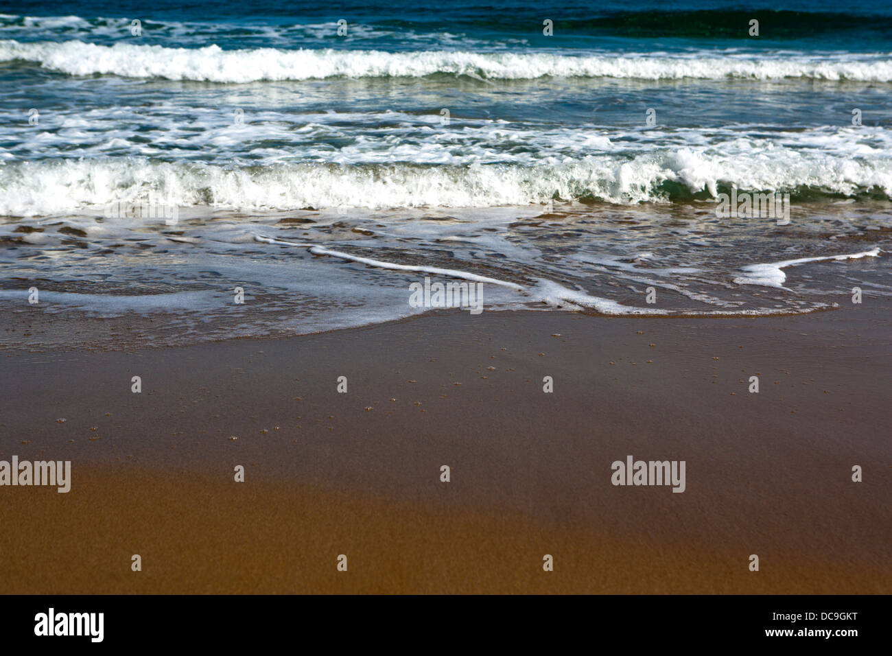 Shallow focus image of surf lapping onto a beach Stock Photo