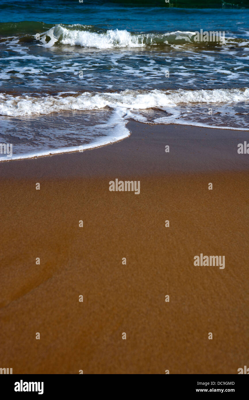 Shallow focus image of waves lapping onto a beach Stock Photo