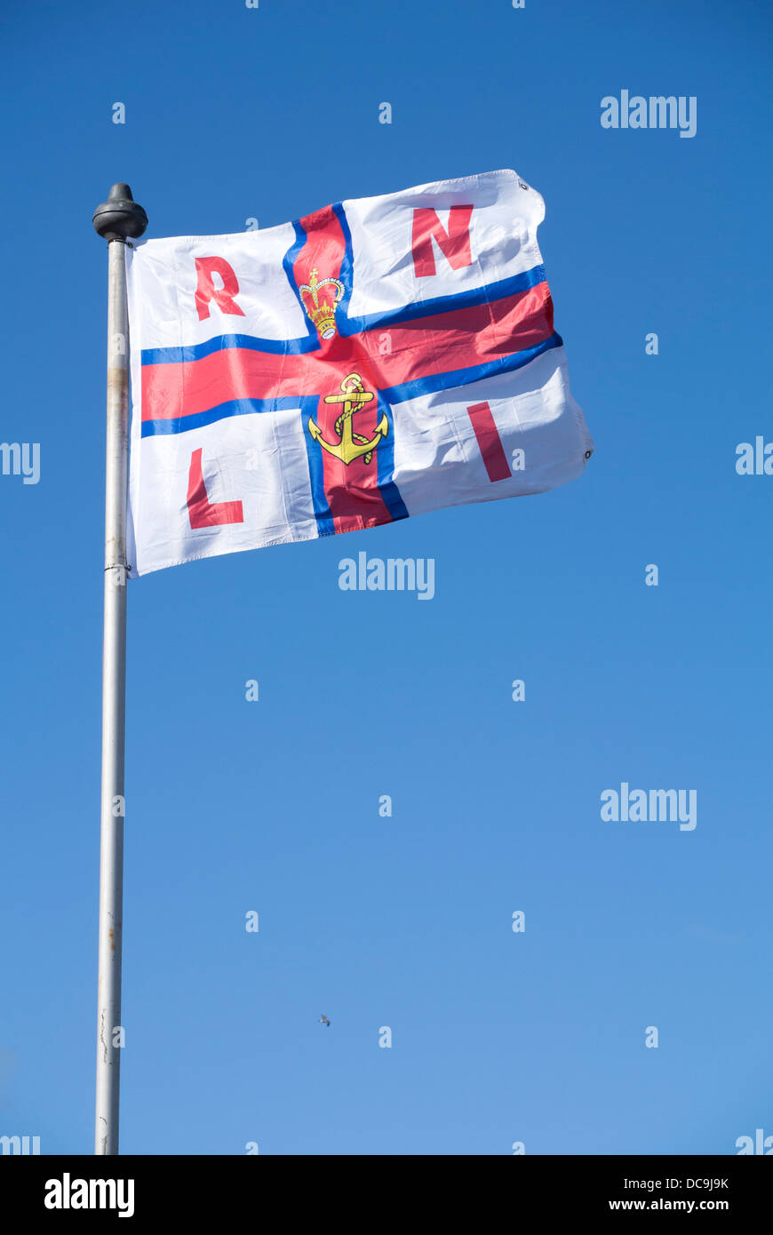 RNLI flag in blue sky blowing in the wind. Stock Photo