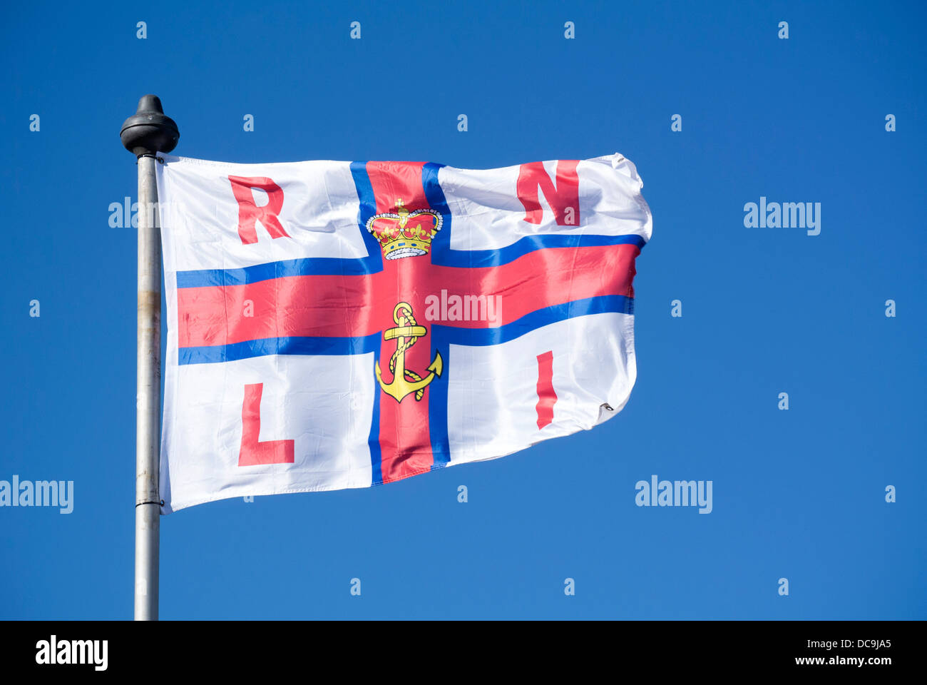 RNLI flag in blue sky blowing in the wind. Stock Photo