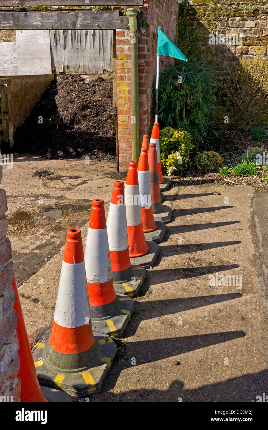 A line of safety cones with a green flag sticking out of the end one