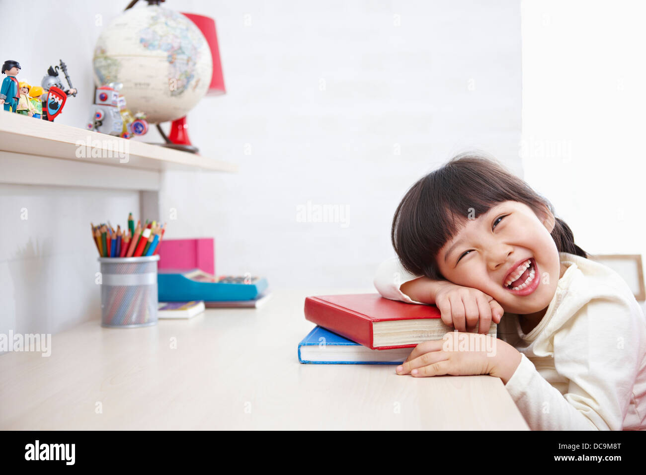 a kid smiling while leaning on a pile of books Stock Photo - Alamy