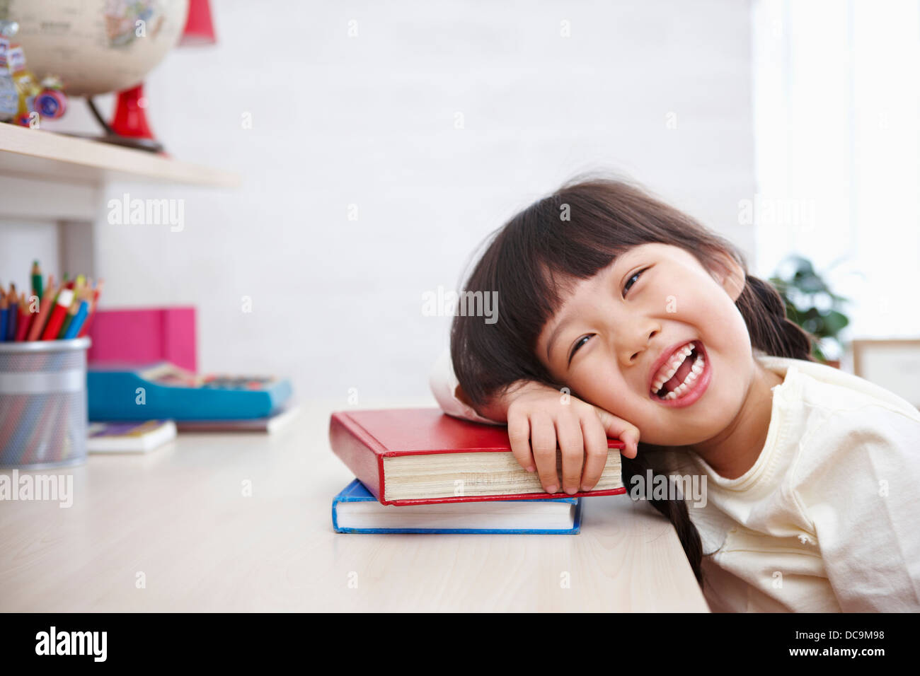 a kid smiling while leaning on a pile of books Stock Photo - Alamy
