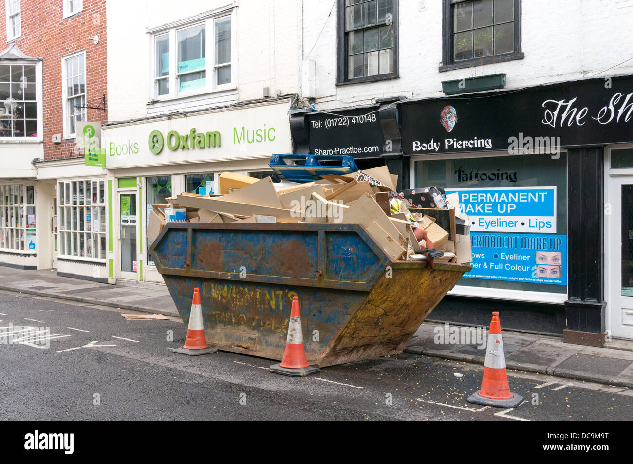 Full skip UK public high street road Stock Photo Alamy
