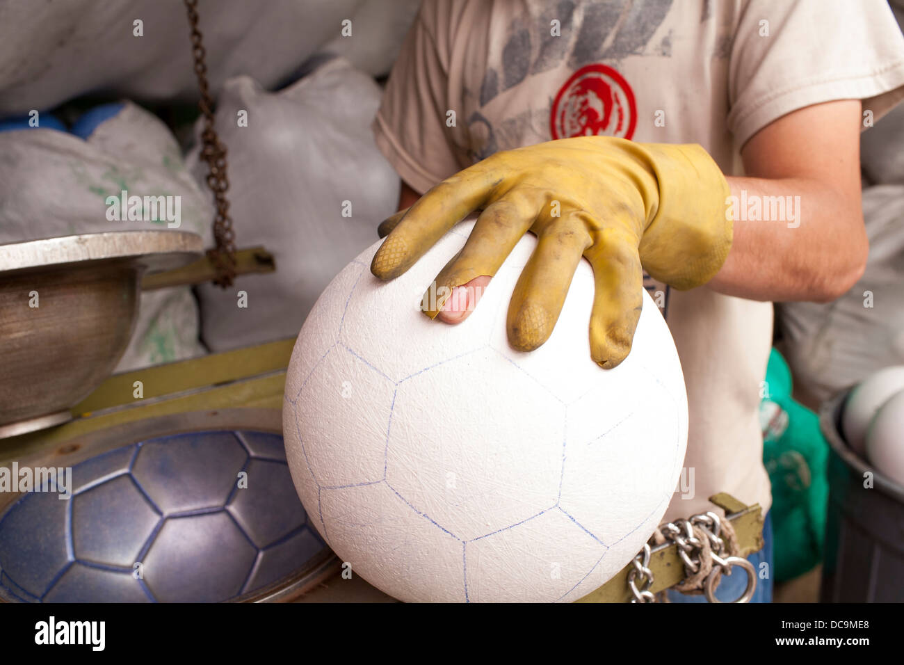 A worker handles a football or volleyball printing the pattern for leather in a factory in Mongui, Boyaca District in Colombia Stock Photo