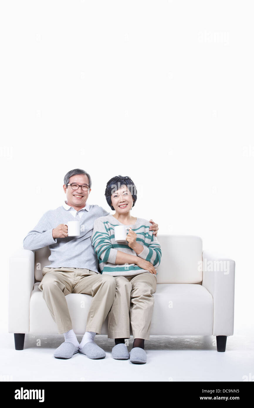 middle aged couple sitting on a couch drinking coffee Stock Photo - Alamy