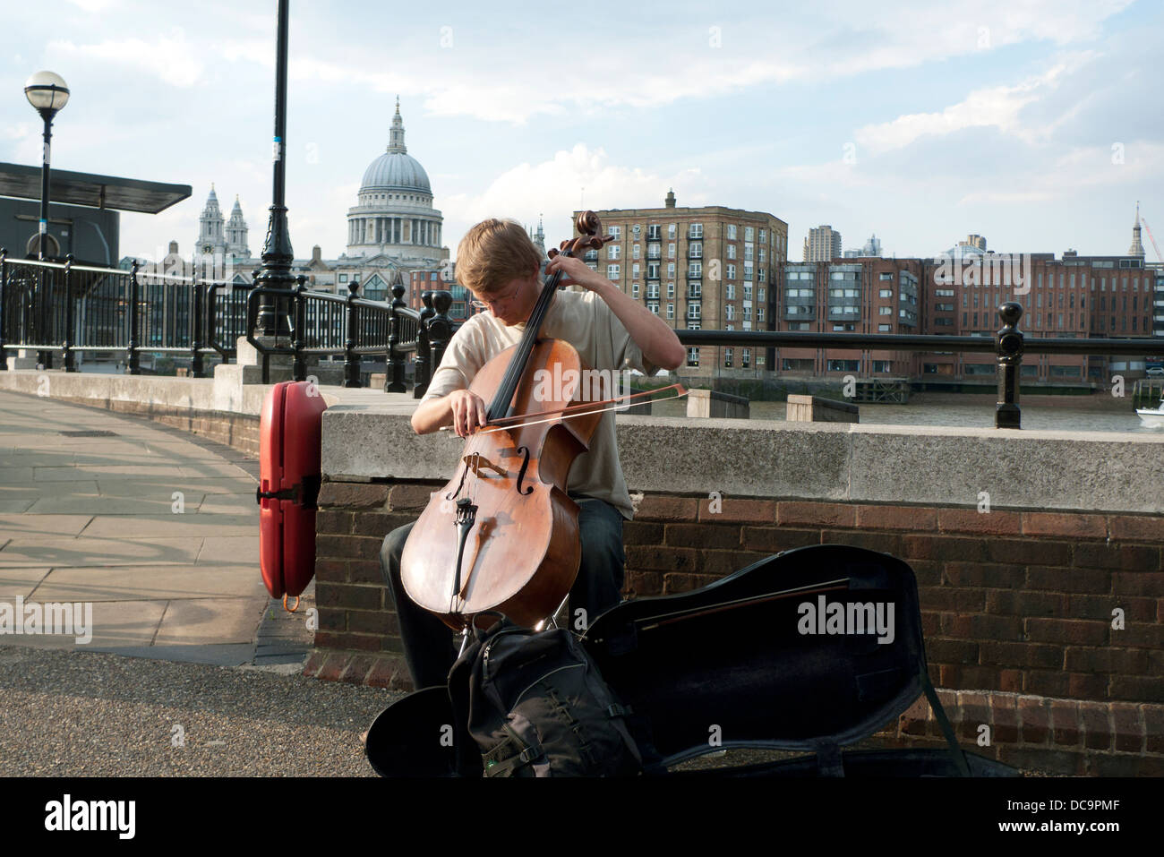 A young man busker playing the classical music on the cello with a view of St. Paul's Cathedral Southbank London England UK Stock Photo