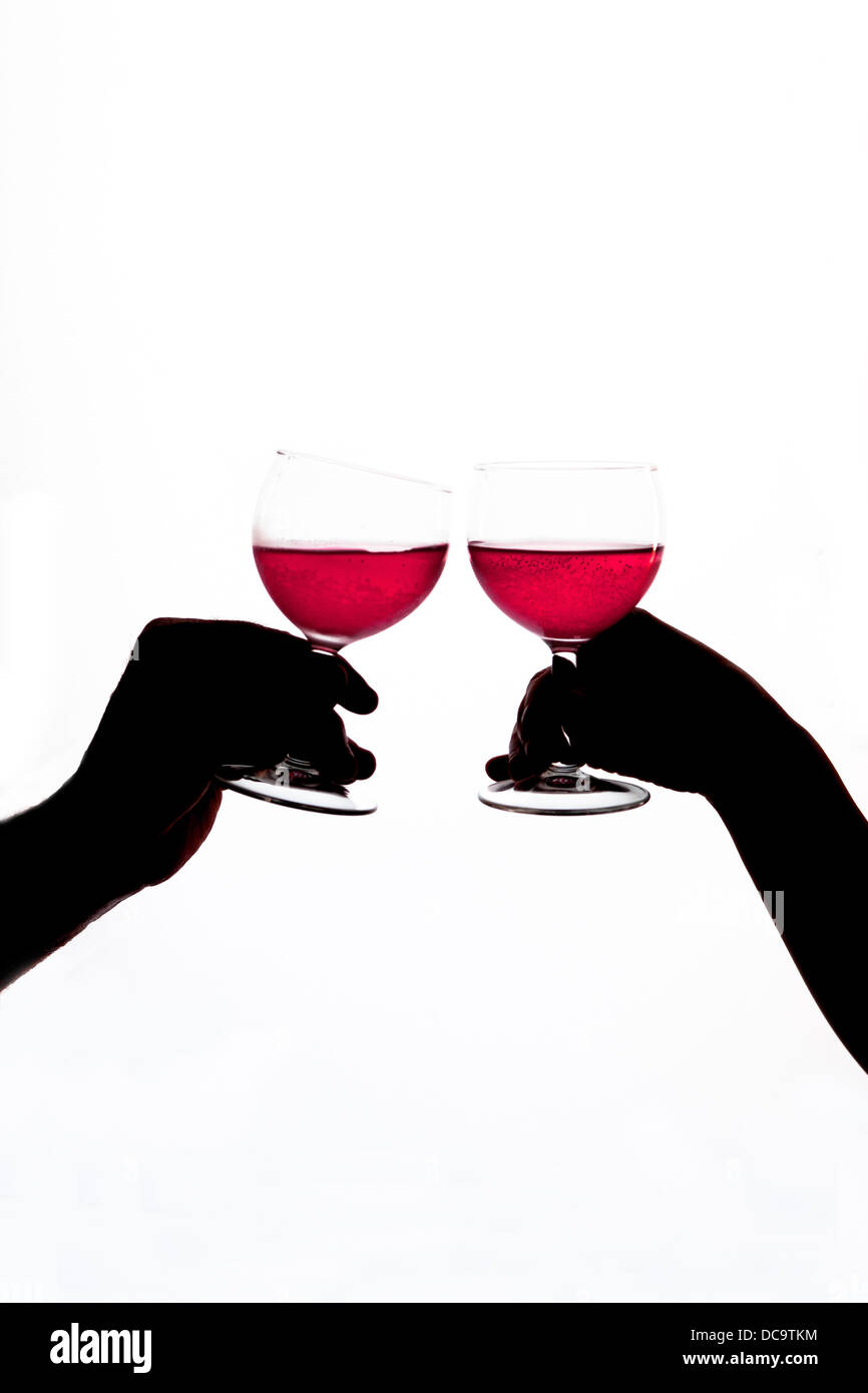 Hands holding glasses of red wine in silhouette against a white background. Stock Photo