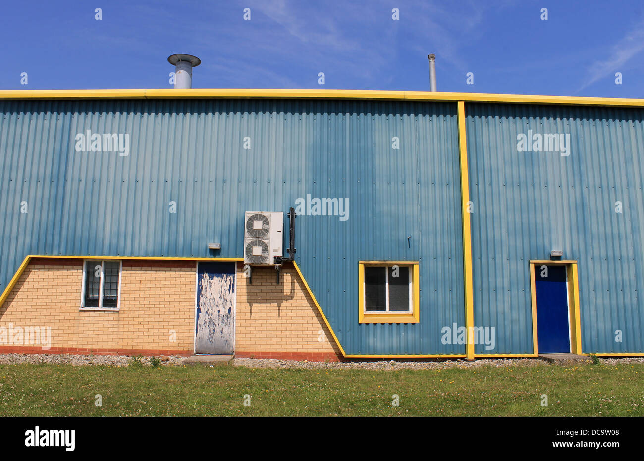 Exterior of blue and yellow warehouse building with air conditioning. Stock Photo
