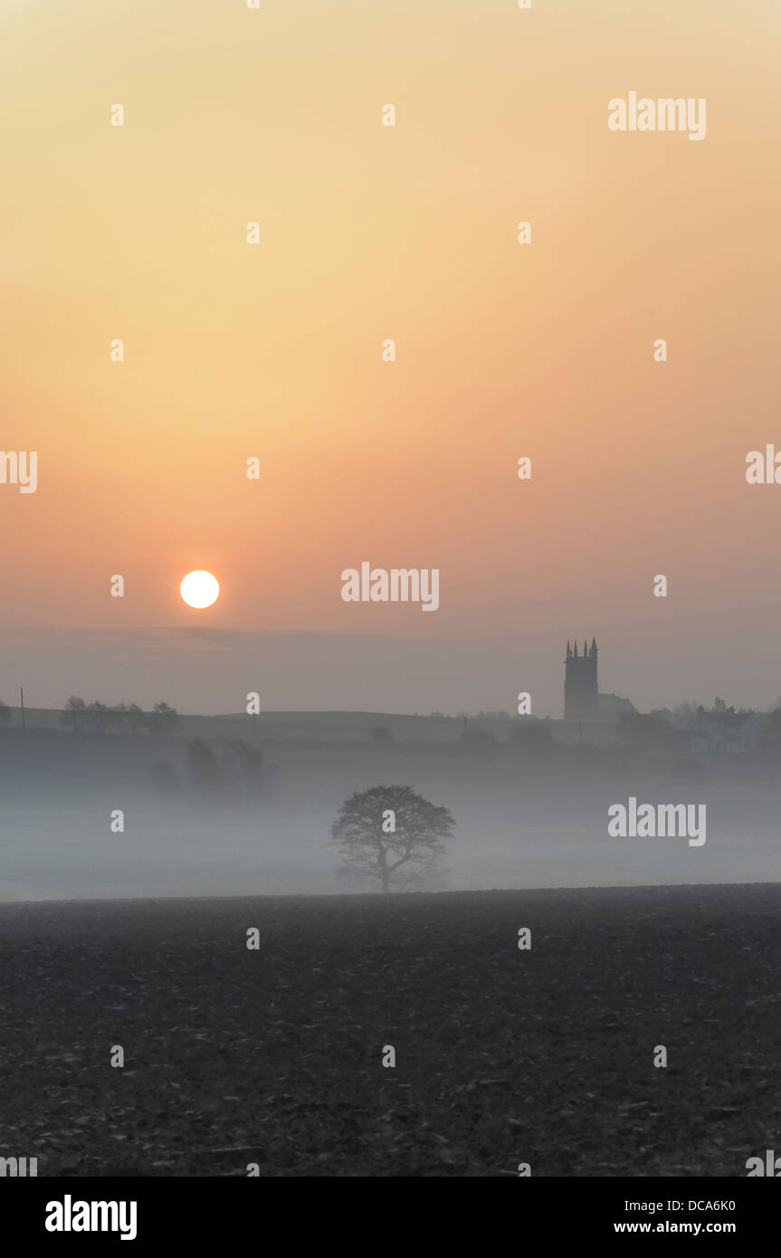The sun rises on a misty morning over Christ Church on Holborn Hill in Aughton, Lancashire, England, UK Stock Photo