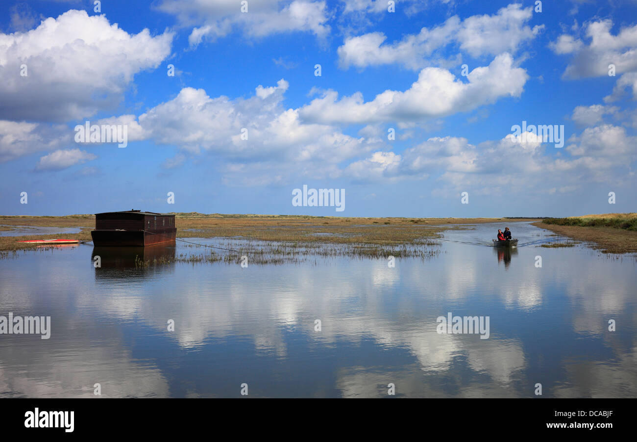 Father and son boating in a flooded creek at high tide on the North Norfolk coast. Stock Photo