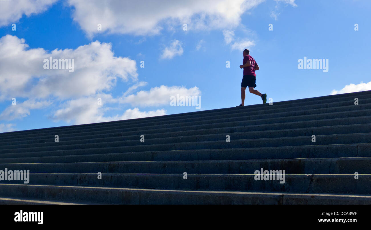 Man running along the top of a sea wall. Stock Photo