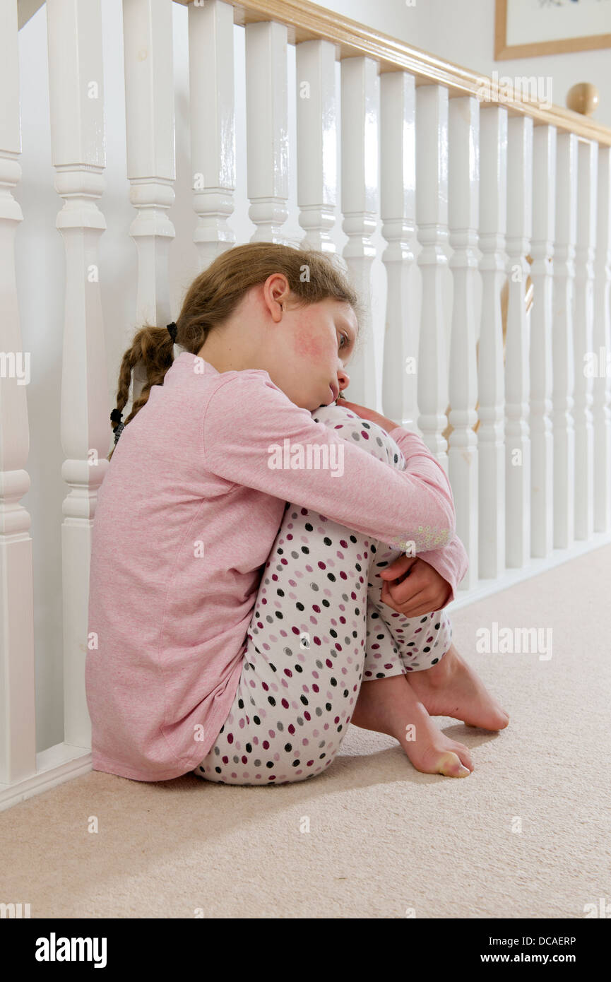 young girl upset sad and lonely holding head in hands crying huddled on ...