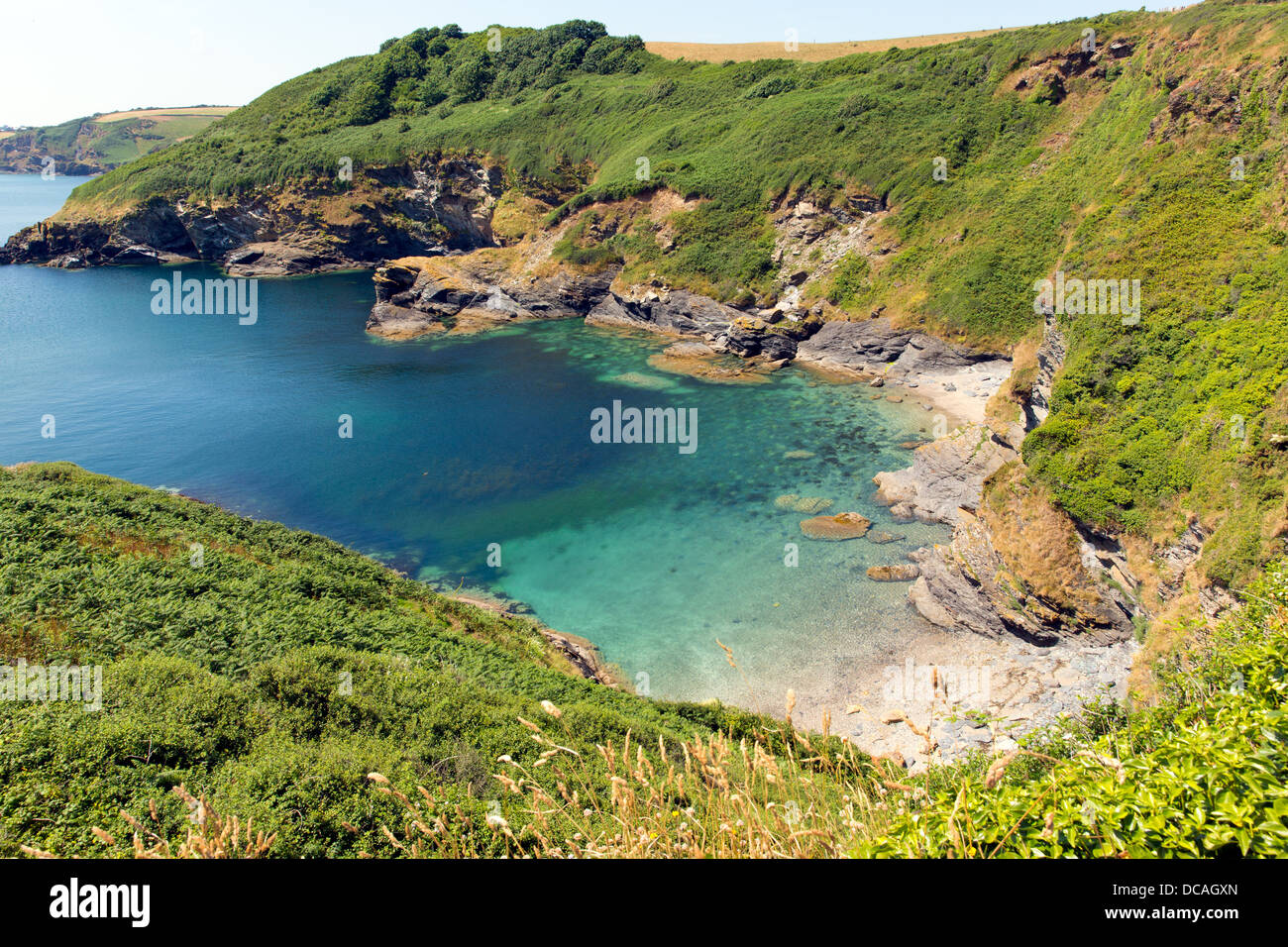 Secluded beach and cove with turquoise sea Black Head headland St Austell Bay between Porthpean and Pentewan Cornwall Stock Photo