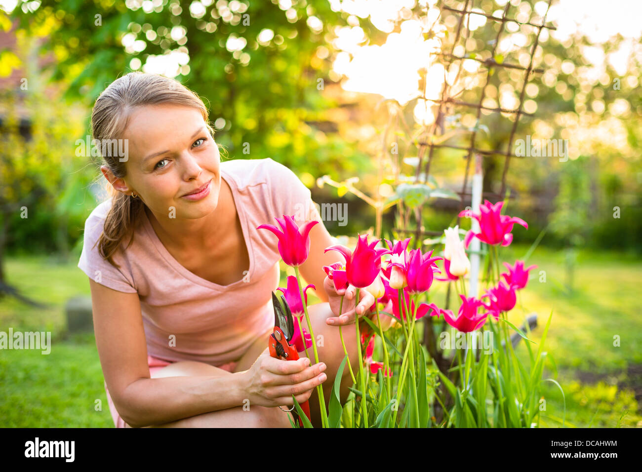 Pretty female gardener taking care of her lovely garden on a spring day ...