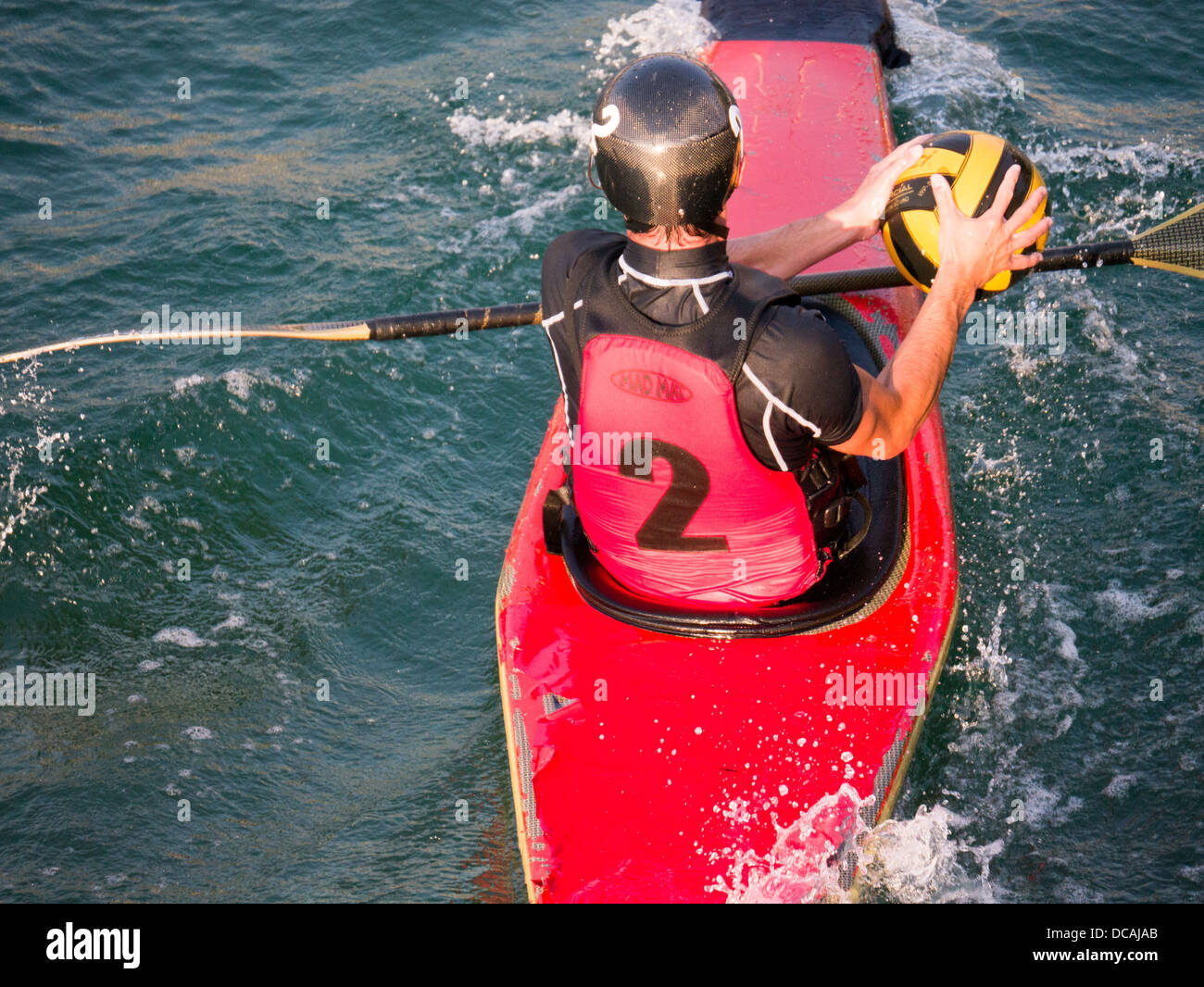 Man in red and black plays canoe polo / kayak polo Stock Photo