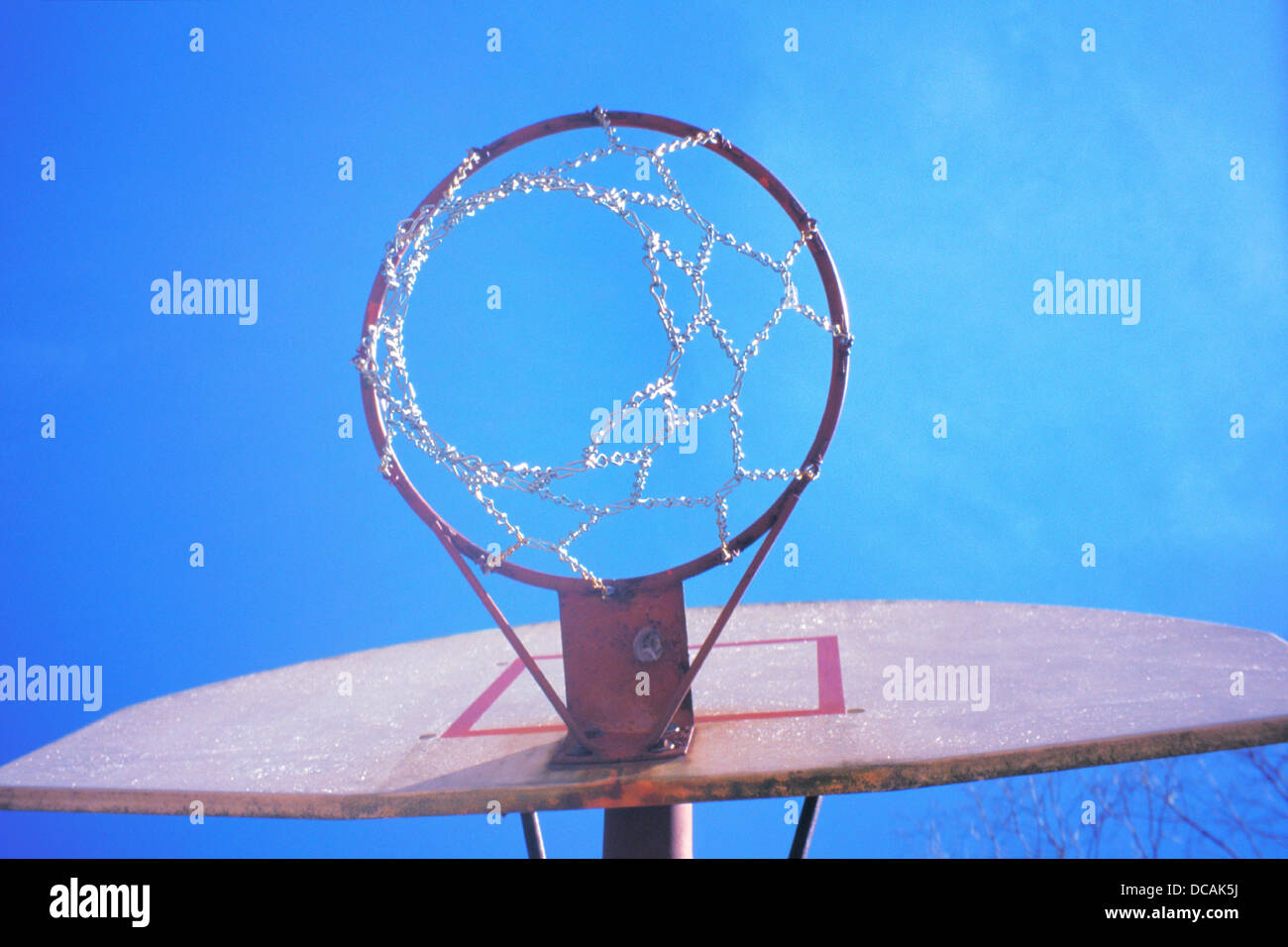 Basketball hoop seen from below, against almostcloudless blue sky