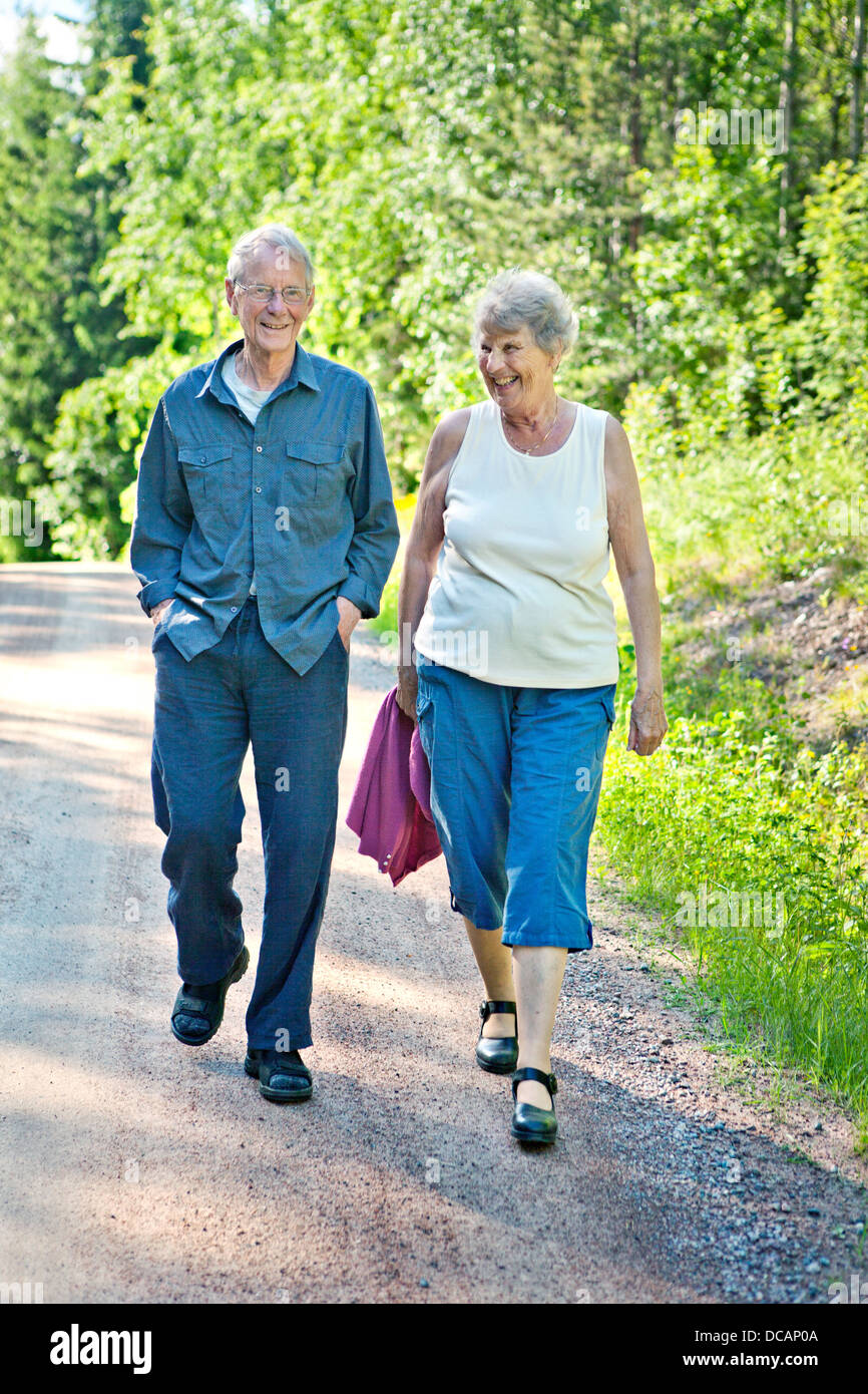 Senior smiling couple walking on country lane in summer Stock Photo