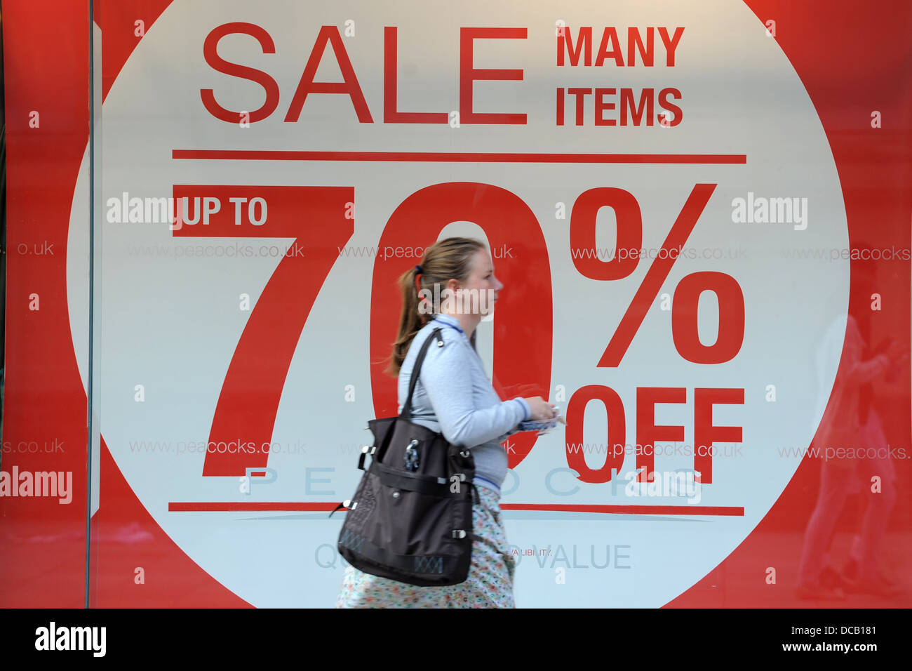 A shopper walks passed a 70% sale sign on the High Street. Stock Photo