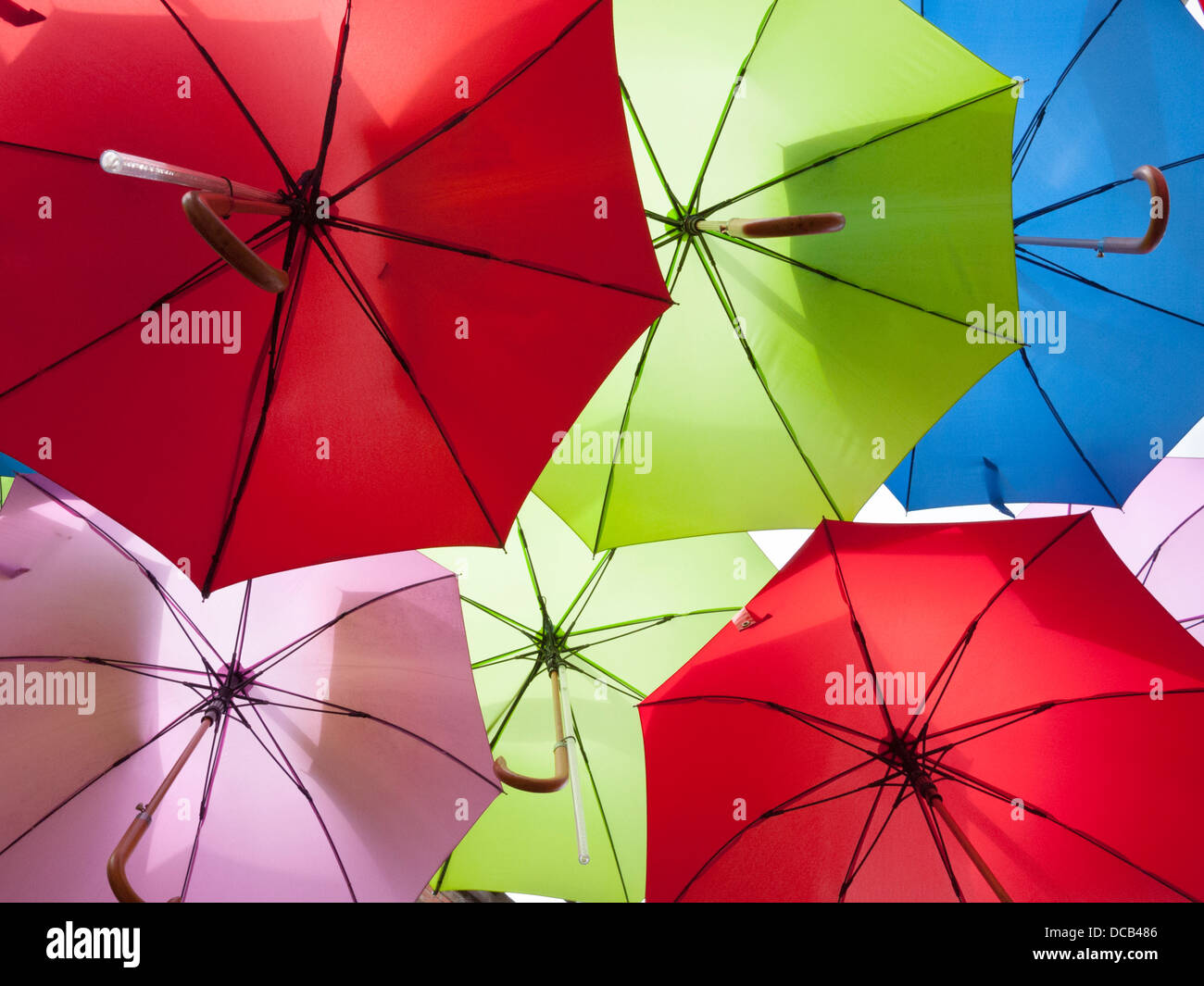 Brightly coloured umbrellas hanging up in a display in London UK Stock
