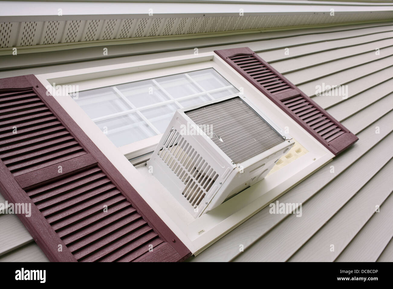 Air conditioner in house window with gray siding Stock Photo