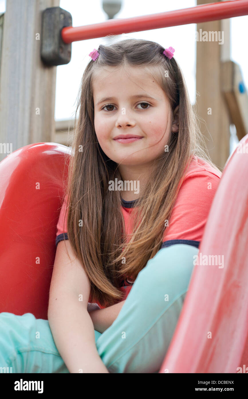 Girl on a playground sitting on a children's slide Stock Photo - Alamy