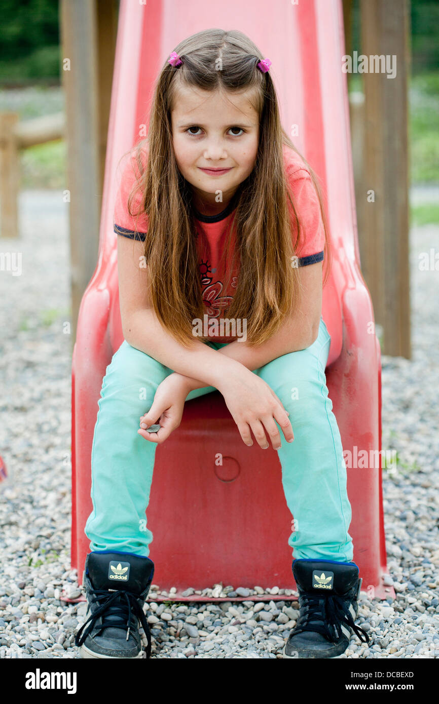 Girl on a playground sitting on a children's slide Stock Photo - Alamy