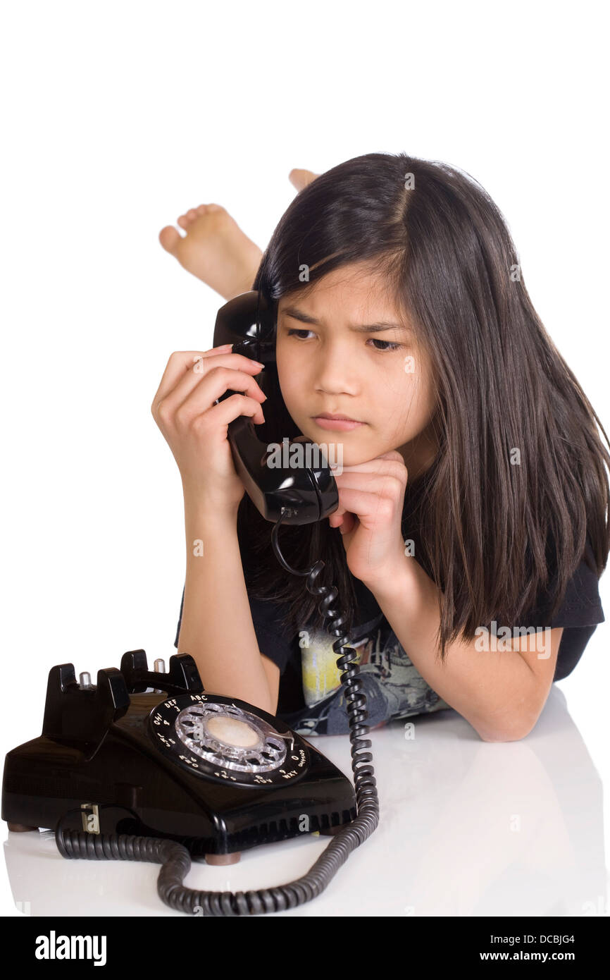 Girl talking on rotary phone, worried expression Stock Photo
