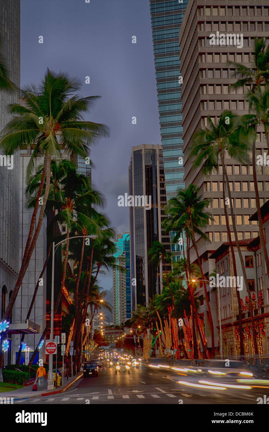 Downtown Honolulu at Bishop Street, dusk HDR, streaming car lights, palm trees and buildings. Stock Photo