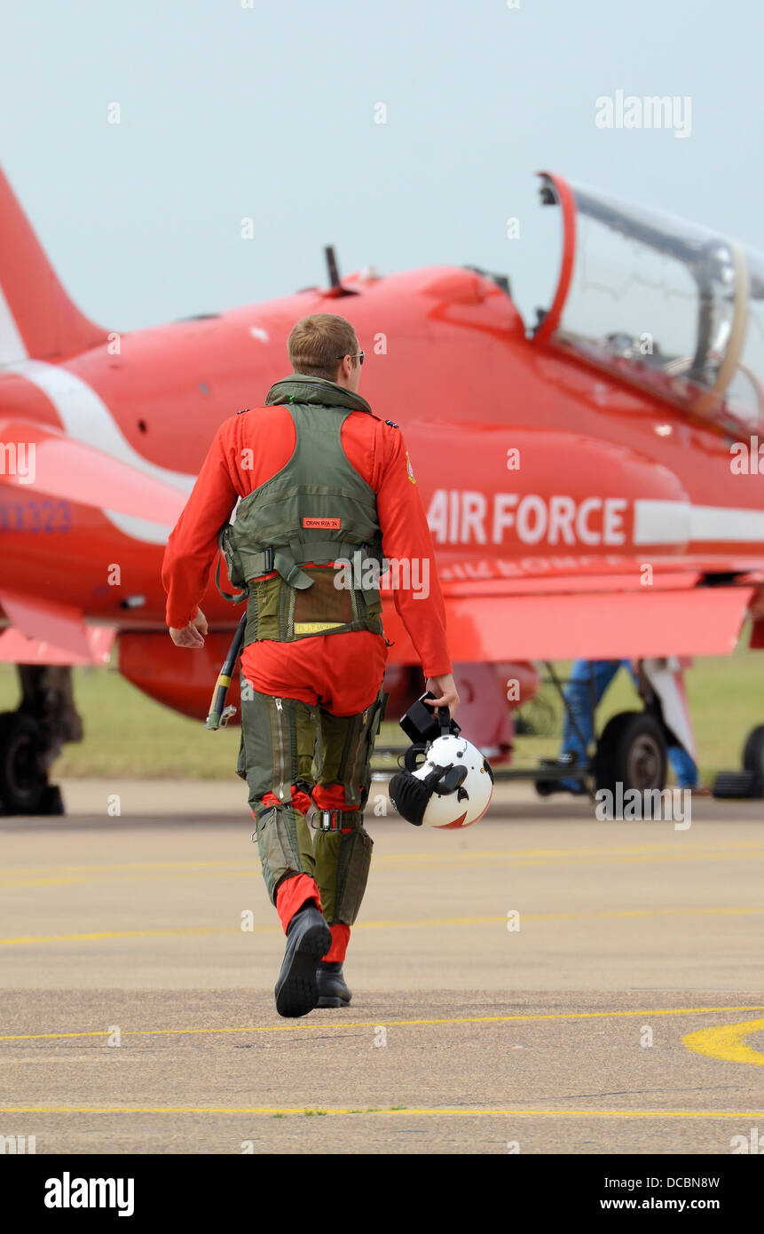 A Red Arrows pilot walks out to his Hawk jet to carry out a display with the team. Wearing a G-suit over his red flying suit. Walking to work Stock Photo
