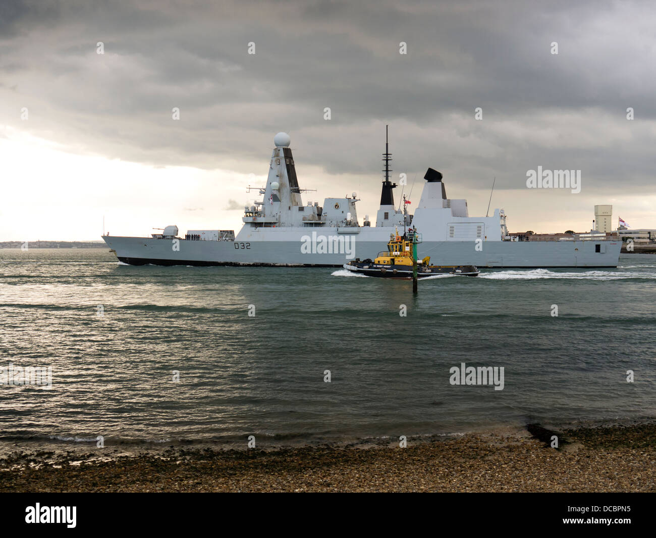 The type 45 class Destroyer HMS Daring, D32, Leaving Portsmouth Harbour accompanied by the tug SD Independent Stock Photo