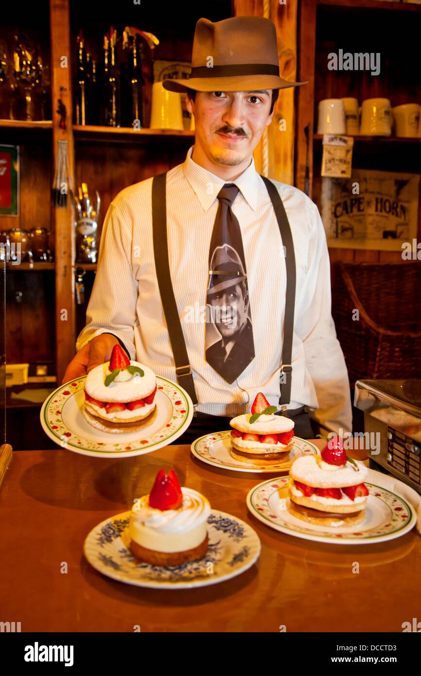 Mozo waiter serves strawberry cream cake while wearing Carlos Gardel tie famous singer/tango dancer from 1920s , Ramos Stock Photo