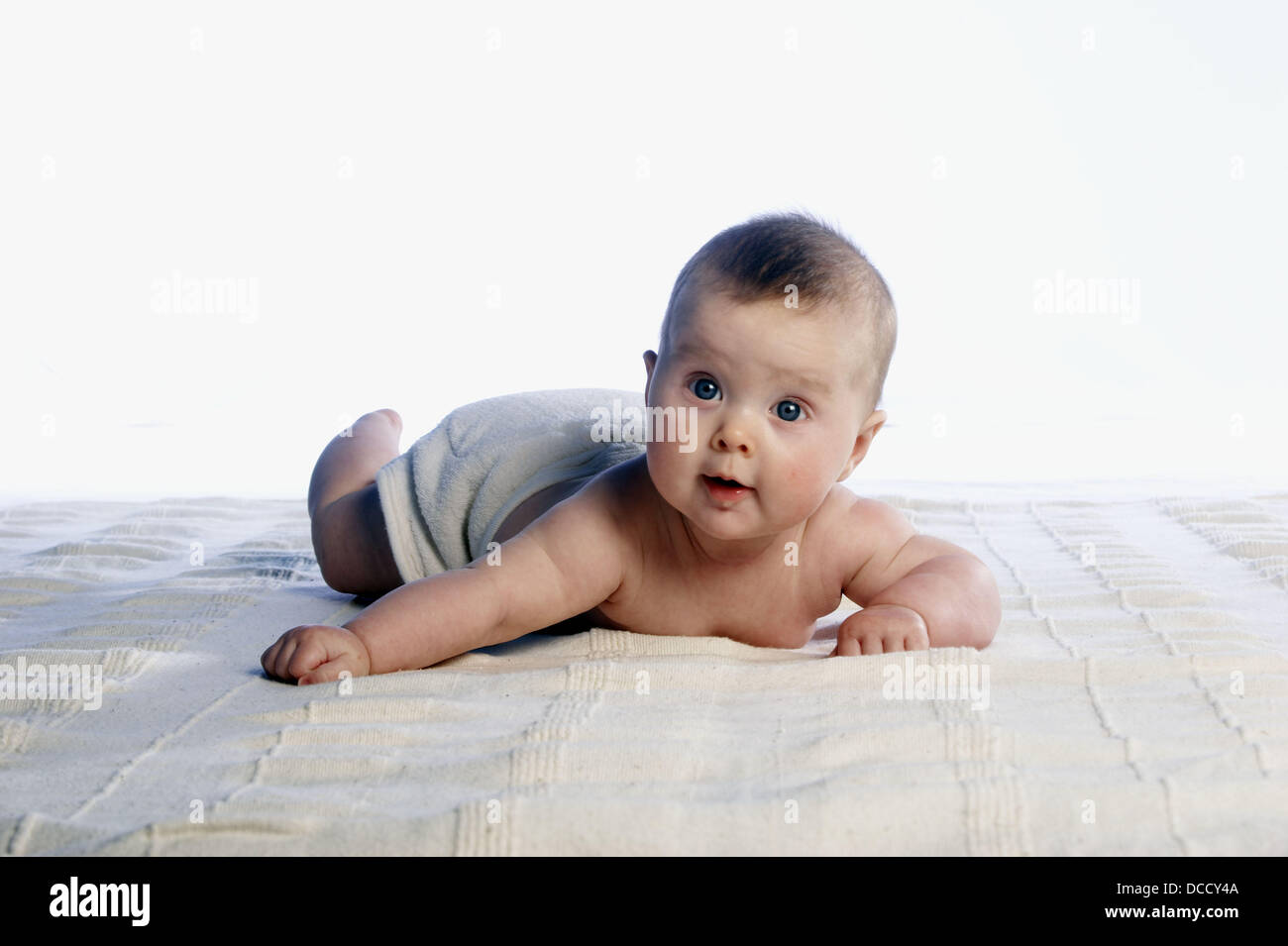 4 month old baby, lying on her tummy smiling off camera, lifting her