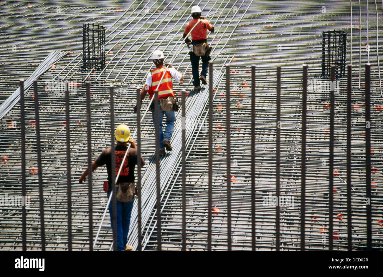 Ironworkers carrying long rebar. I880 Cypress Project. Oakland