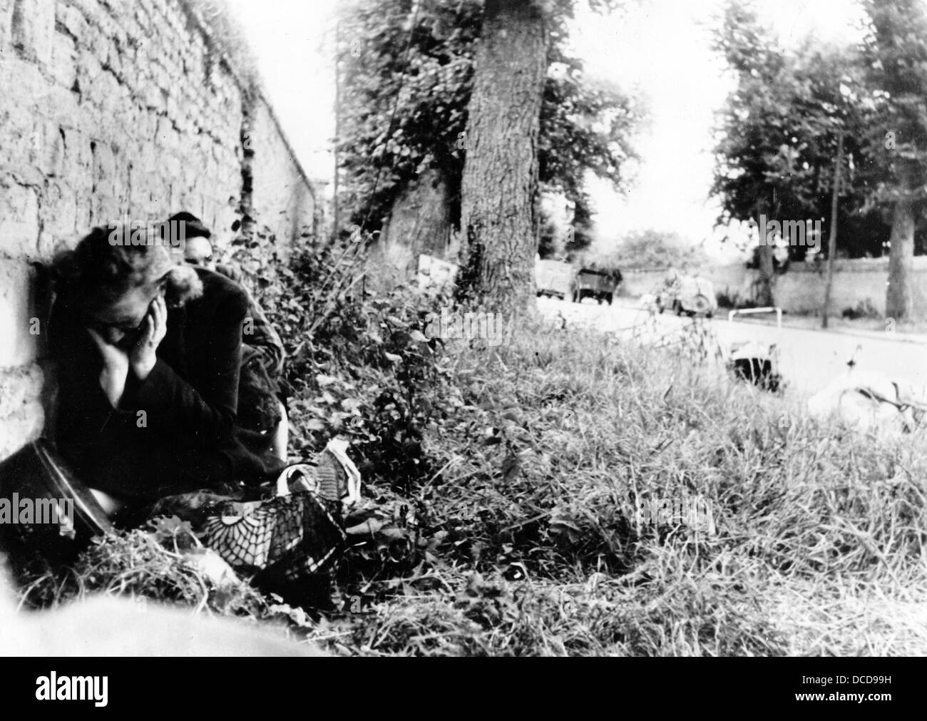 Two women are on the run and take shelter from enemy air raids behind a wall during the Battle for Caen in France in July 1944. Fotoarchiv für Zeitgeschichte Stock Photo