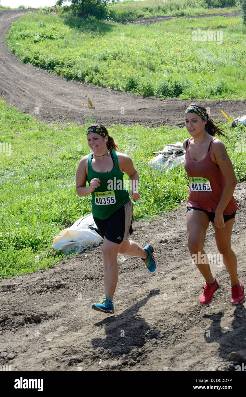 Two woman running  in 5K mud race. Stock Photo