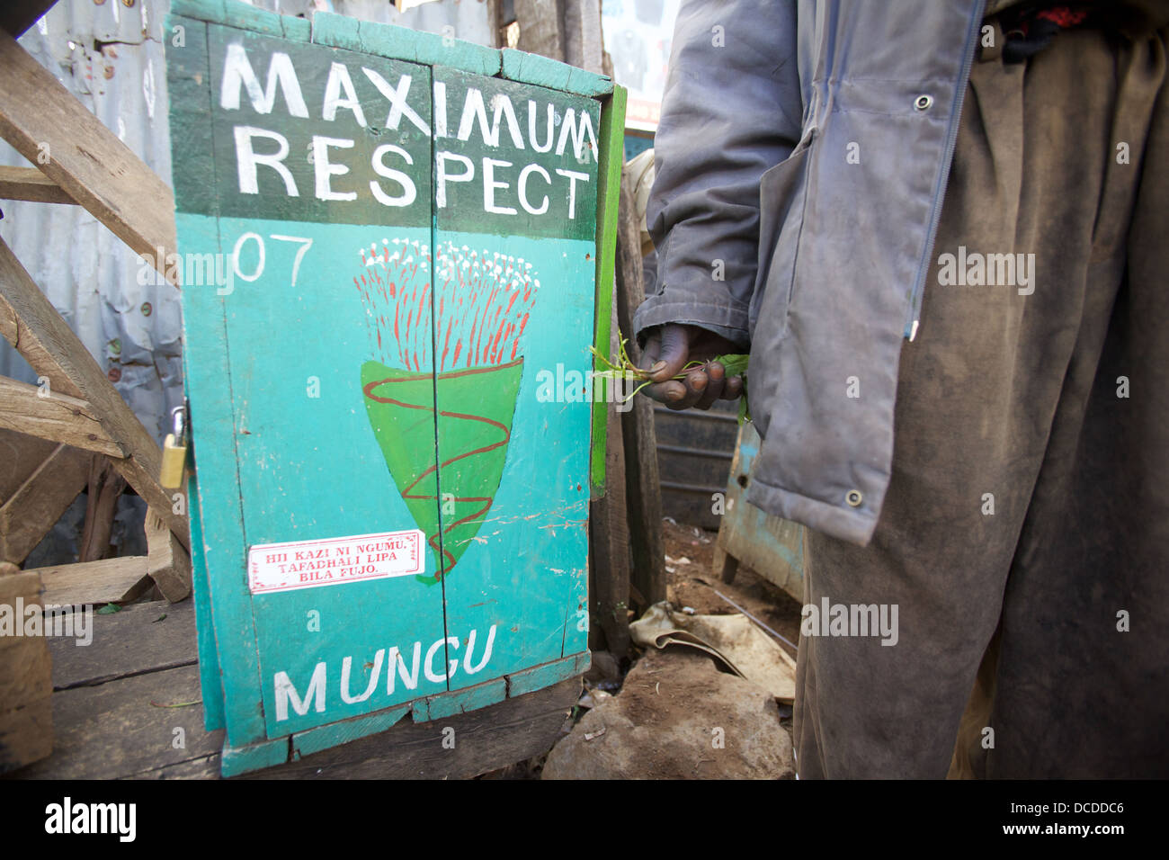 Hand holding khat next to a painted sign advertising khat bundles and