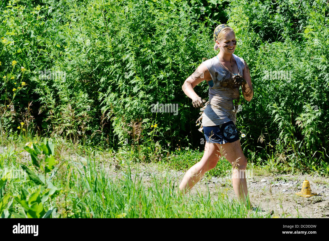 Woman running in race covered in mud. Stock Photo