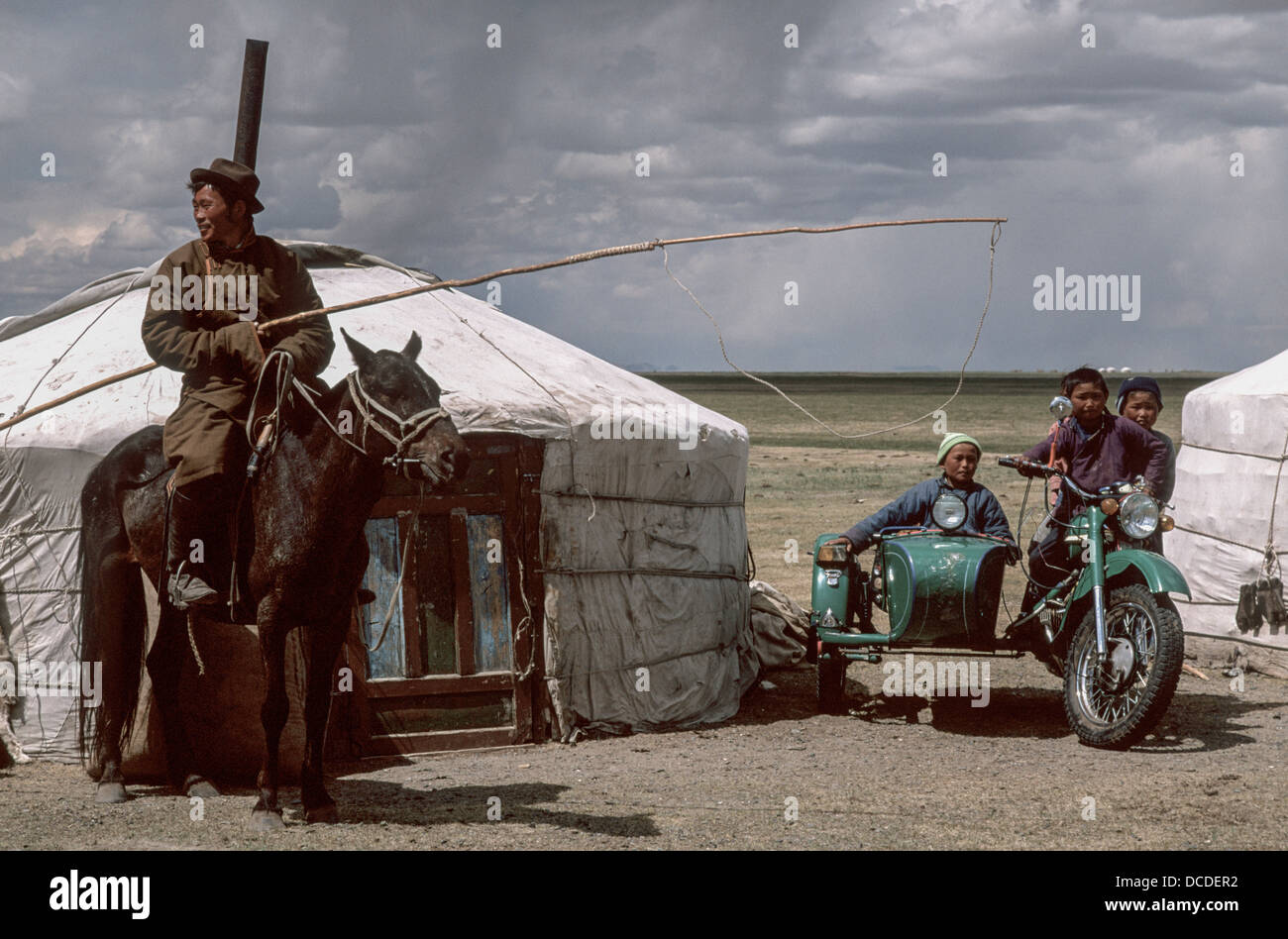 Mongolian men and children on horse and children on motor bike in front ...