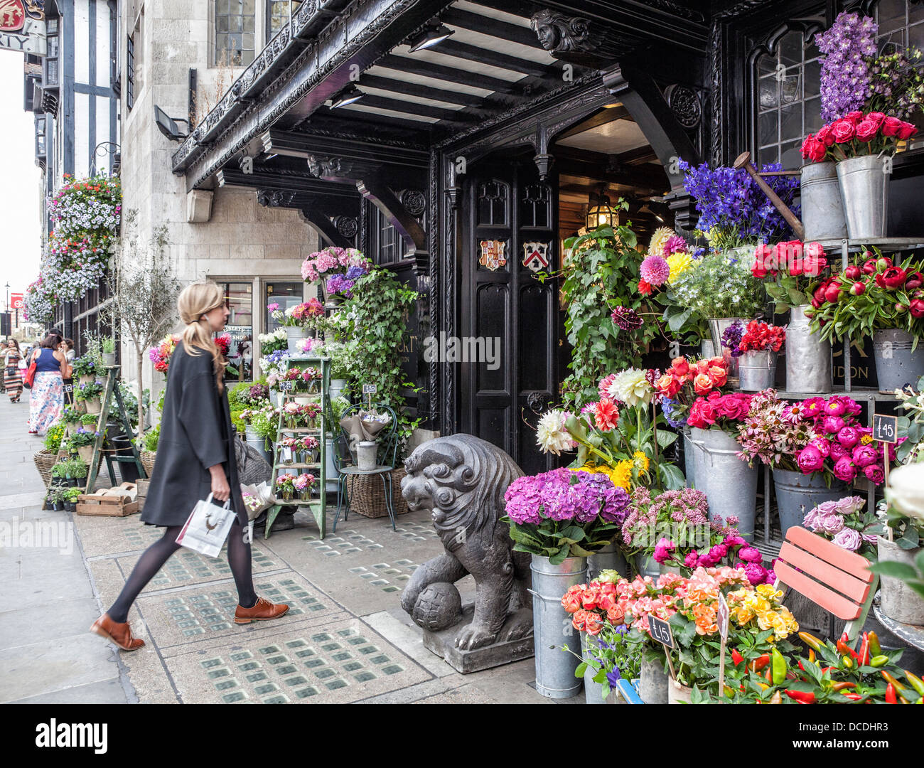 A young woman approaches the entrance to the flower shop of the Liberty Department Store, London Stock Photo