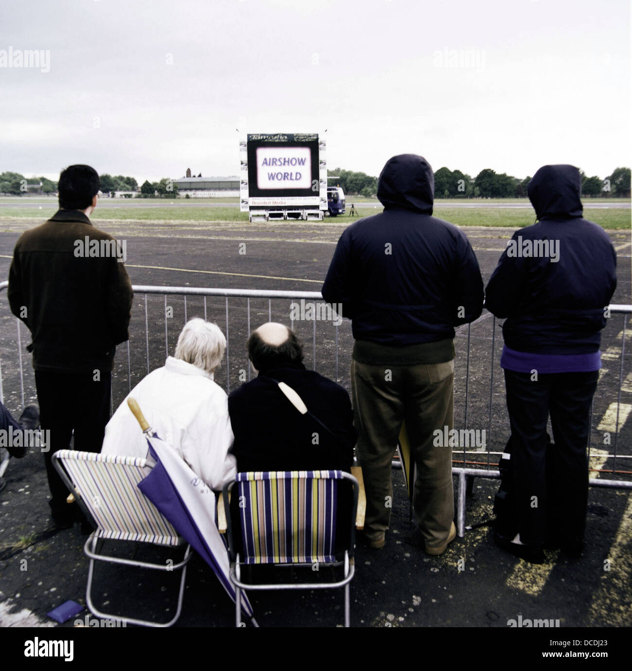 Waiting for the airshow to commence, an aviation enthusiast family huddle in the cold at Mildenhall, a US Air Force base in Suffolk, England. Stock Photo