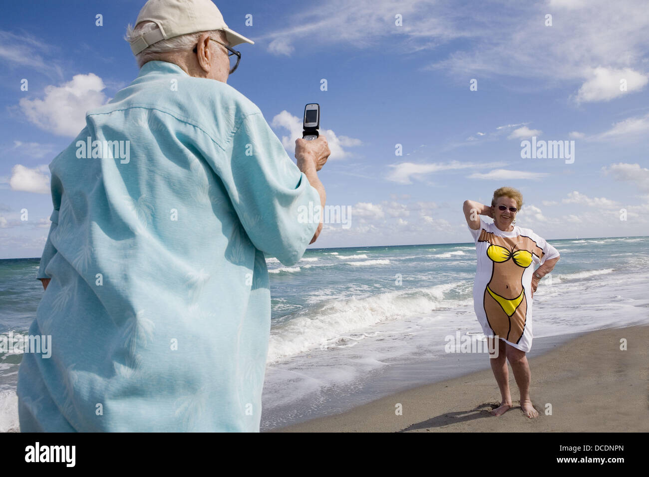 Taking picture of wife in humorous tee shirt at beach Stock Photo