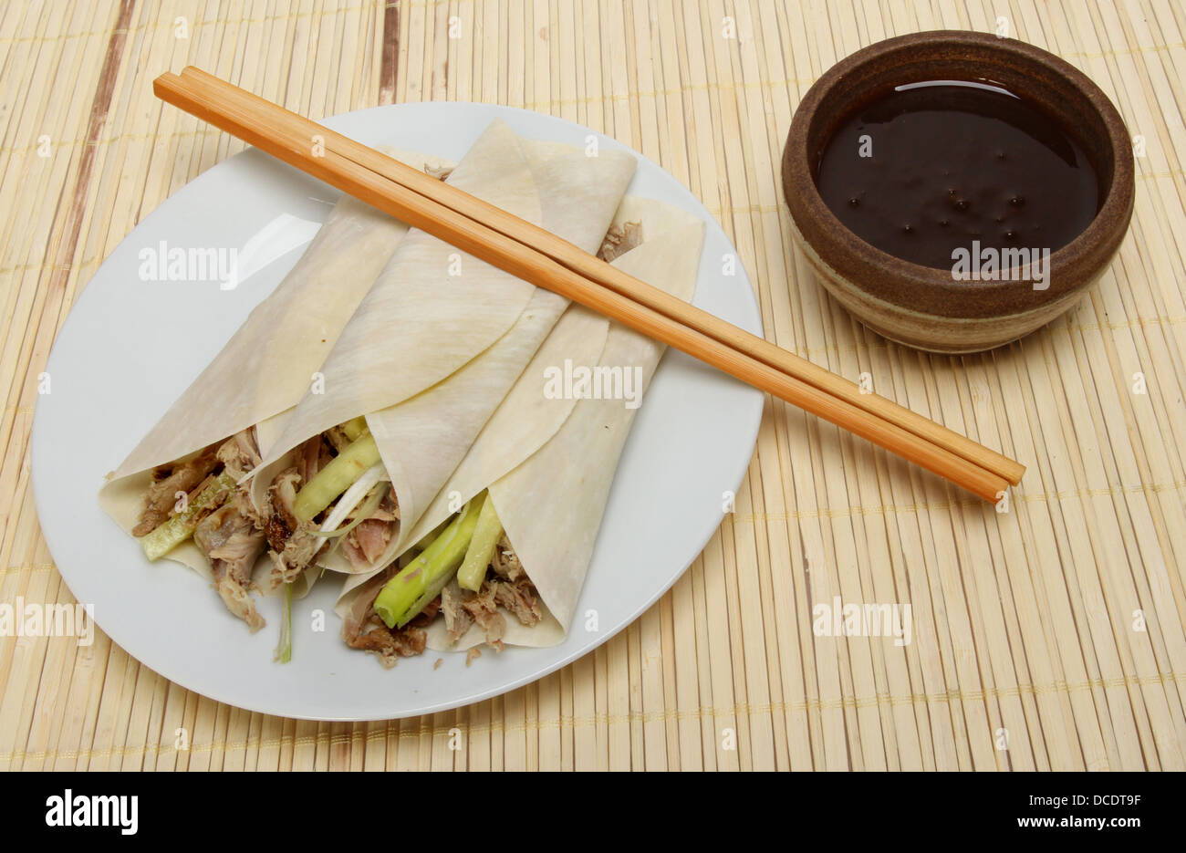 Chinese crispy duck pancakes, hoisin sauce and chopsticks on a bamboo matt Stock Photo
